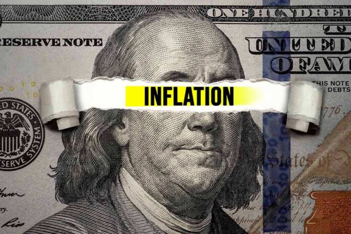 A torn paper strip with the word 'INFLATION' over a hundred dollar bill featuring Benjamin Franklin