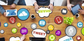 Top view of a collaborative workspace with social media icons and people using laptops