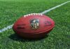 An NFL football resting on a green grass field