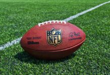 An NFL football resting on a green grass field