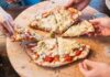 People sharing slices of pizza on a wooden board