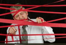 A man tangled in red tape while trying to sign a contract