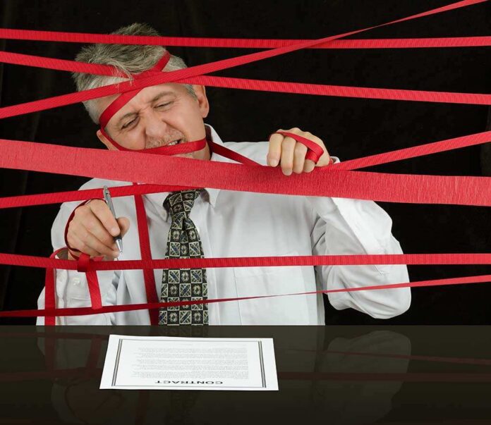 A man tangled in red tape while trying to sign a contract