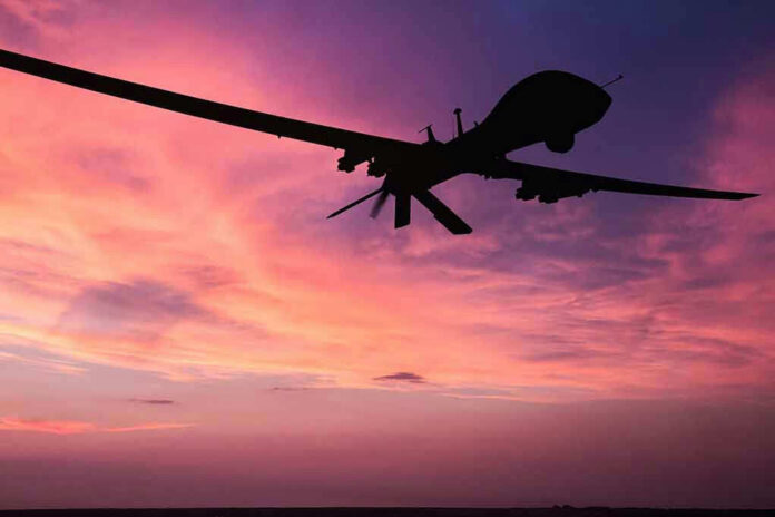 Silhouette of a drone against a colorful sunset.