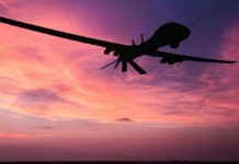 NEW WEAPON Crushes Drone Swarms Silhouette of a drone against a colorful sunset.