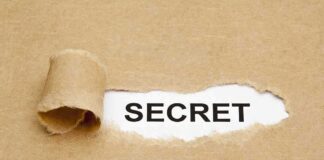 A torn piece of brown paper revealing the word SECRET underneath