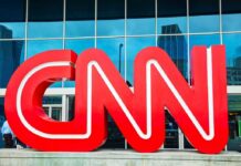 Large red CNN logo in front of a glass building
