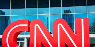 Large red CNN logo in front of a glass building
