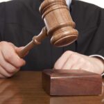 A judge holding a gavel above a wooden block