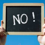 LONE GOP Senator Torpedoes Trump’s DHS Pick A hand holding a chalkboard with the word NO written on it against a blue sky