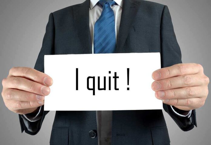 A man in a suit holding a sign that says I quit