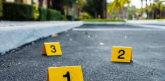 Crime scene markers on asphalt with bullet casing.
