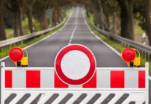 Traffic barrier with a red and white sign blocking a road