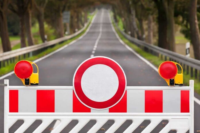 Traffic barrier with a red and white sign blocking a road