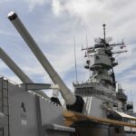 Iran’s Oil Chokepoint—Trump’s Next Move Close-up of a battleships naval guns and superstructure against a cloudy sky