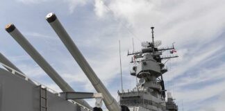 Close-up of a battleships naval guns and superstructure against a cloudy sky