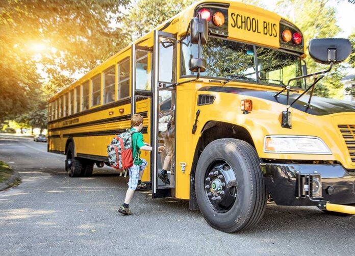 shutterstock_314871770.jpg A child with a backpack boarding a yellow school bus