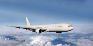 A white airplane flying above fluffy clouds in a blue sky