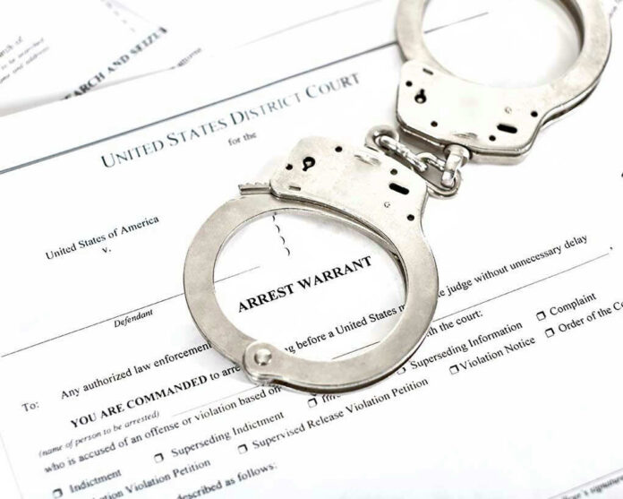 1316784506 Handcuffs on top of an arrest warrant document.