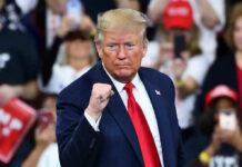 Michelle Obama’s Jaw-Dropping Trump Voter Analysis Man in suit making a fist gesture at rally.