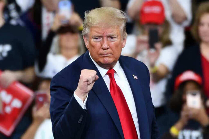 1585235176 Man in suit making a fist gesture at rally.
