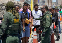 Border patrol agents inspecting group of individuals in line.