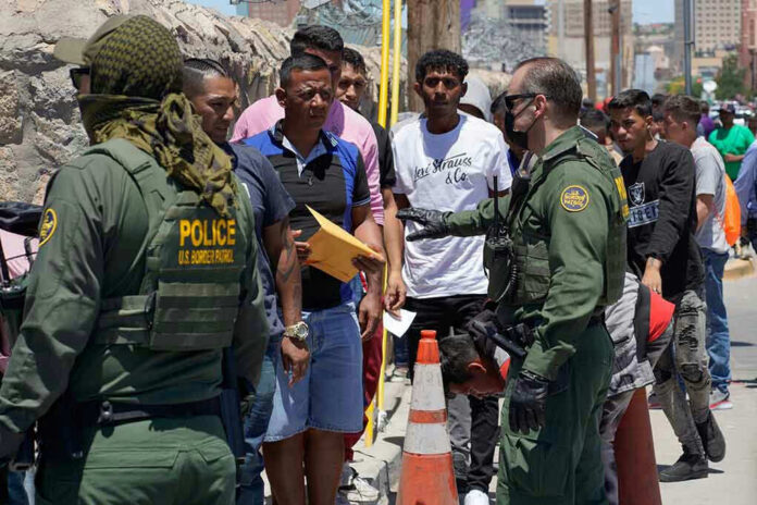 2300859029 Border patrol agents inspecting group of individuals in line.