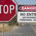Airport HORROR: Trespasser Meets Tragic End Stop and Danger signs on a chain-link fence.
