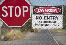 Stop and Danger signs on a chain-link fence.