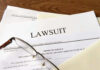 Abrams-Linked Nonprofit Scandal EXPLODES! Documents labeled Lawsuit with glasses on top.