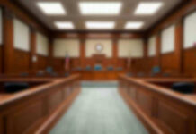 Empty courthouse courtroom with wooden benches and chairs.
