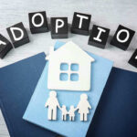 Adoption blocks, books, house, and family paper cutouts.