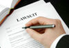 He Stole From Hungry Kids… Then Vanished Hand holding pen, filling out lawsuit form.