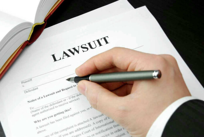 93505333 Hand holding pen, filling out lawsuit form.