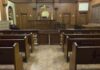 Interior view of an empty courtroom with wooden benches and a judges bench