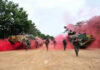 Soldiers running from armored vehicles with red smoke.
