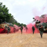 Robot Truck Plants 1,000 Mines — No Driver Soldiers running from armored vehicles with red smoke.