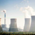 China Overtakes U.S. Nuclear Crown Four cooling towers of a power plant emitting steam.