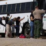 Immigration Enforcement Just Got Turned Into ‘Mega-Project’ Border patrol officers investigating people near a bus.