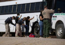 Immigration Enforcement Just Got Turned Into ‘Mega-Project’ Border patrol officers investigating people near a bus.