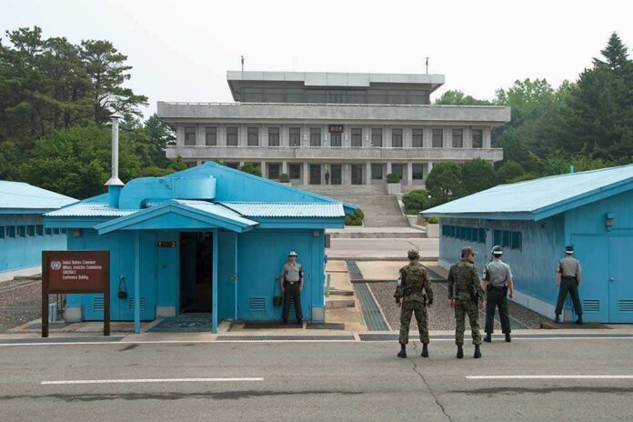 Military personnel standing near blue buildings at a border crossing