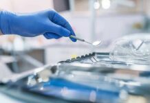 Gloved hand holding a dental mirror over instrument tray