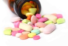 A variety of colorful pills and tablets spilled from a brown medicine bottle