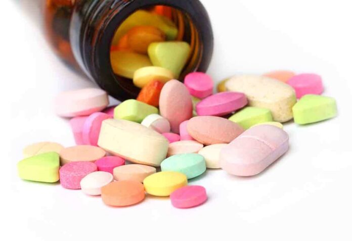 A variety of colorful pills and tablets spilled from a brown medicine bottle