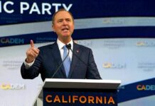Man in suit speaking at a podium with microphones