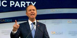 Man in suit speaking at a podium with microphones