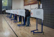 Election Lies Mint Millions — The Game Exposed Voters at polling booths in a gymnasium