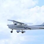 Single-engine airplane flying against a cloudy sky