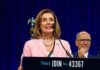 woman in pink blazer speaking at a podium