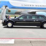 Presidential motorcade limousine parked beside large blue and white aircraft